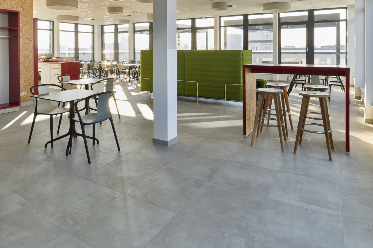 Modern, light grey large-format porcelain tiles in a bright communal space.