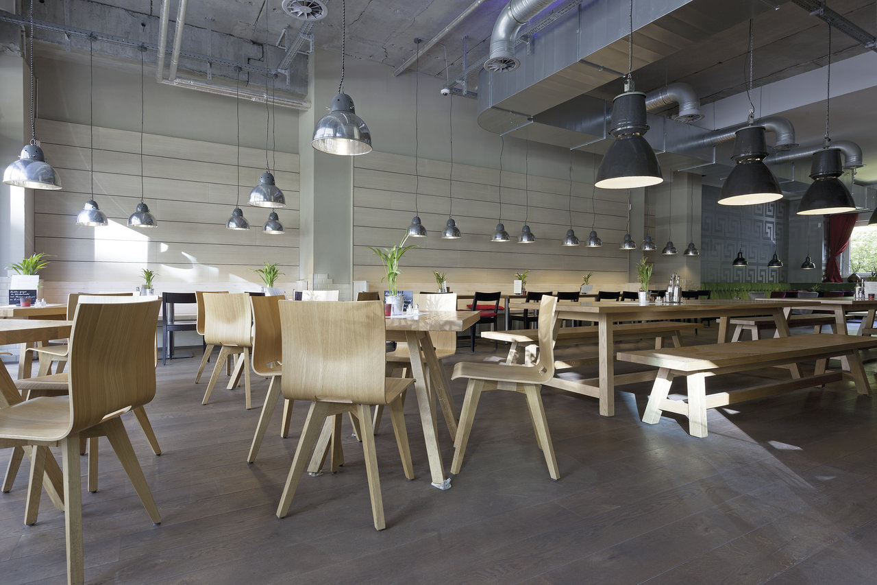 Spacious, bright interior with wooden tables and a modern concrete-effect tiled floor.