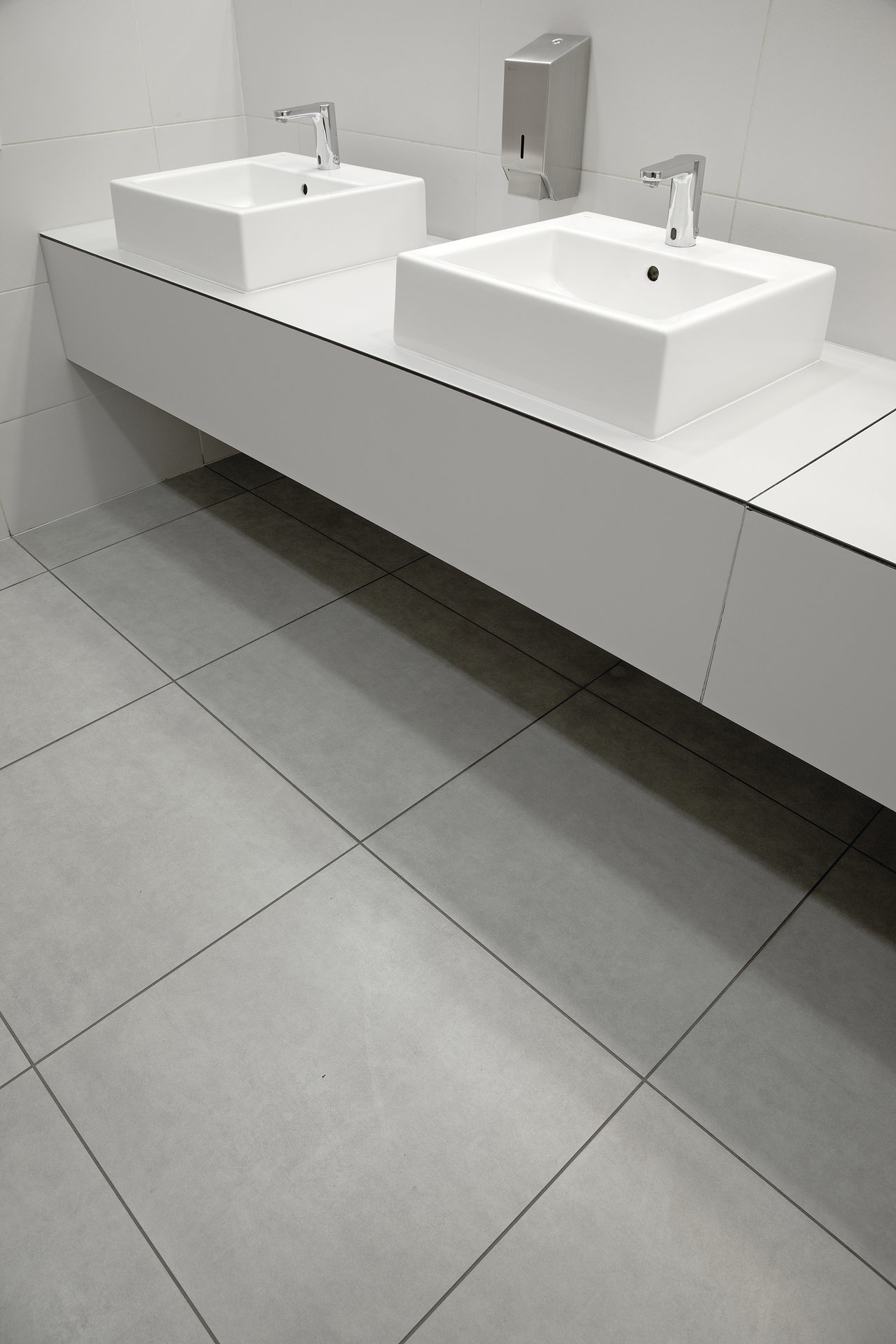 Modern, light grey bathroom tiles under a double vanity.