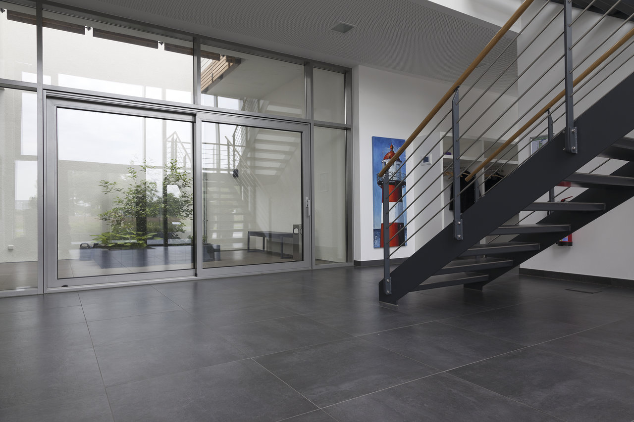 Spacious entrance area with modern dark grey floor tiles and glass front.