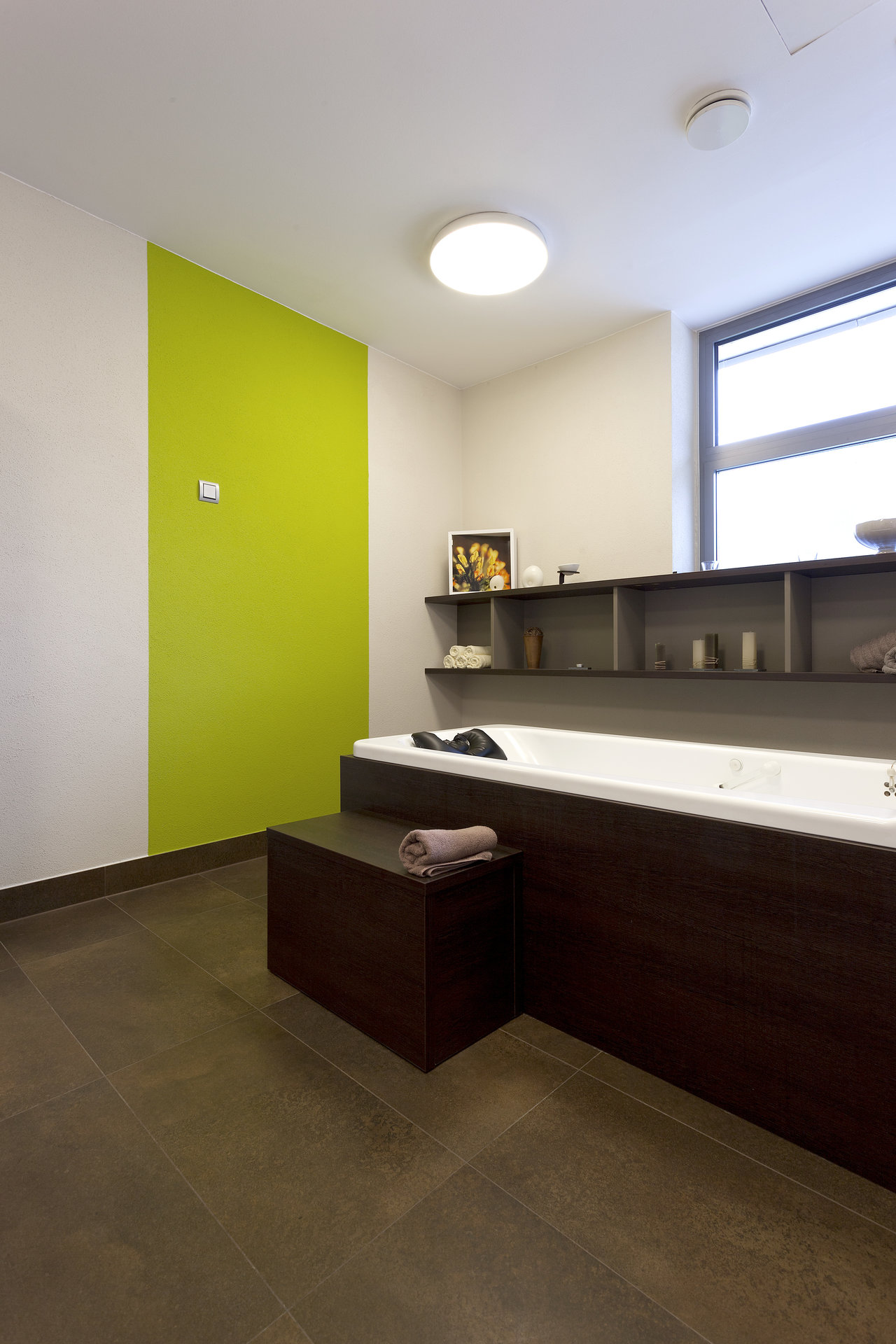 Modern bathroom with dark, large-format floor tiles and a green accent wall.
