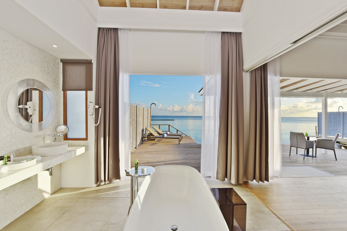 Elegant bathroom with light floor tiles, mosaic wall, and sea view.