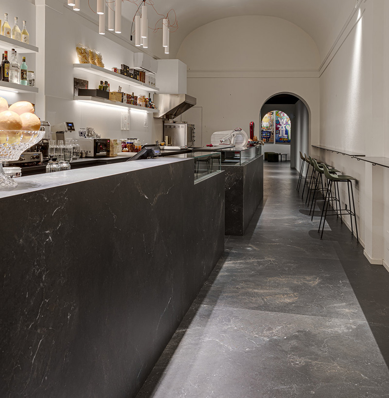 Large-format, dark grey stone-effect tiles on the floor and counter of a café.