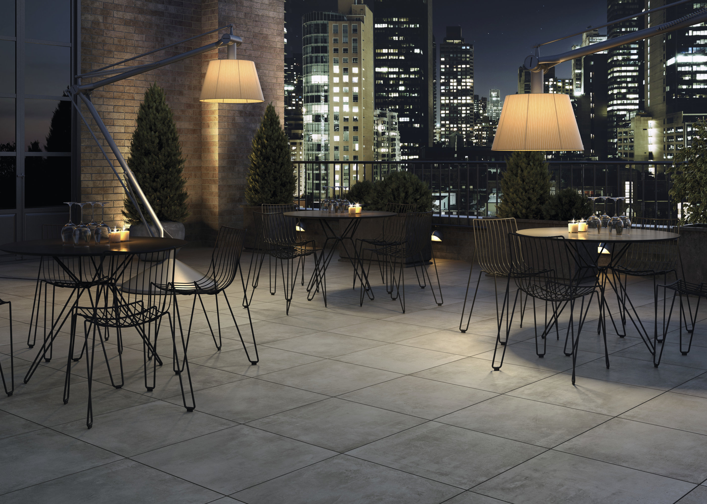 Dachterrasse bei Nacht mit eleganten Outdoor-Fliesen und beeindruckender Stadtsilhouette.