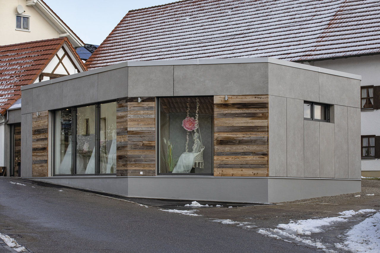 Modern building facade with large-format grey tiles and wood panelling.