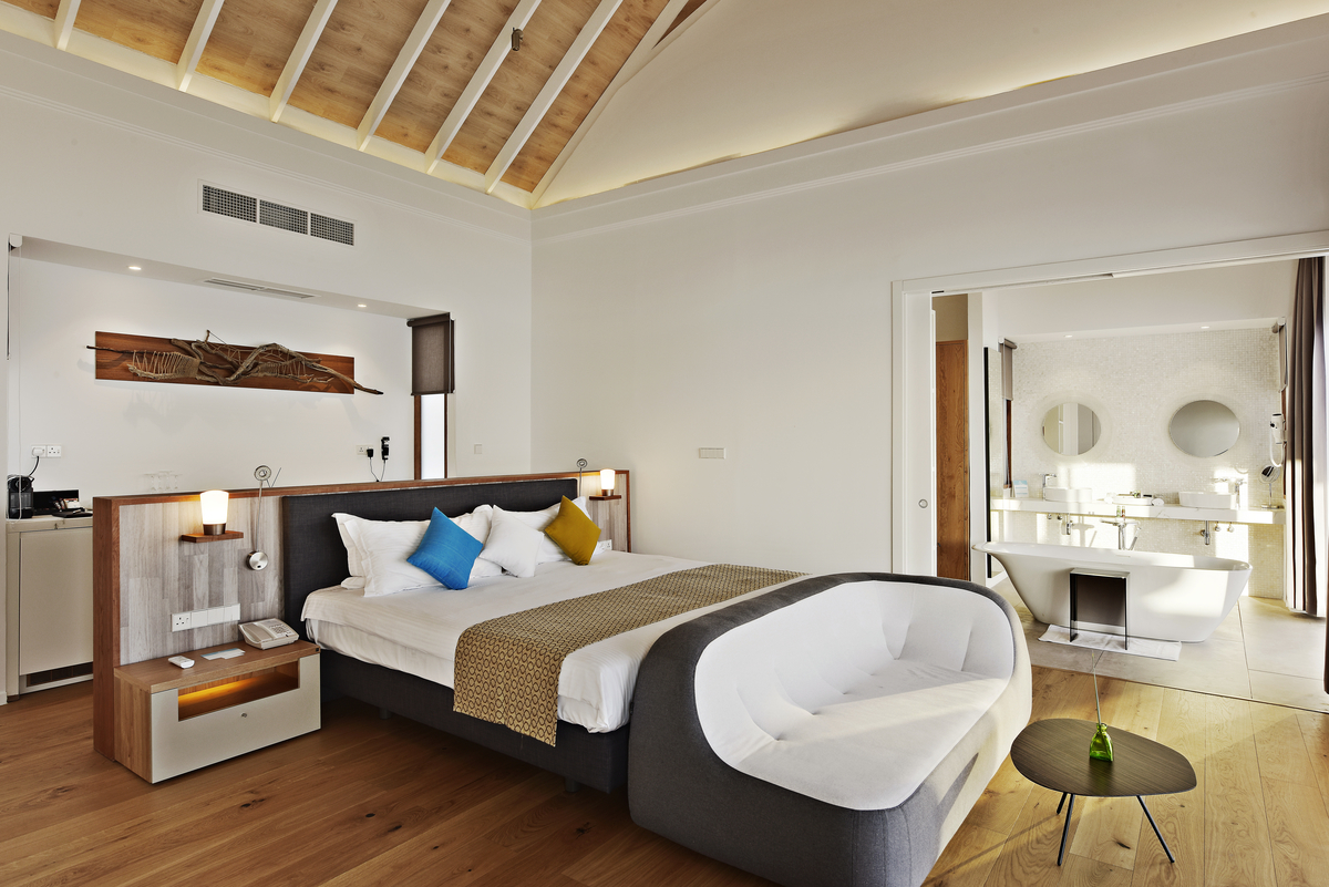Modern bedroom with wood-look flooring and open-plan bathroom, ideal for stylish tile solutions.