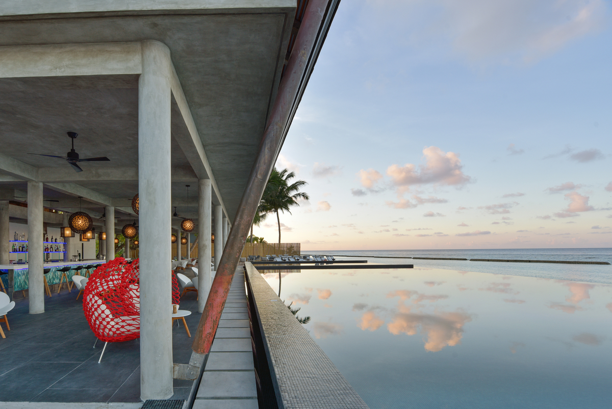 Modern outdoor area with high-quality tiles, stylish bar, and infinity pool by the sea.