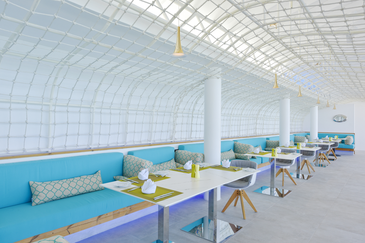 Modern restaurant interior with bright tiles and turquoise upholstered benches.
