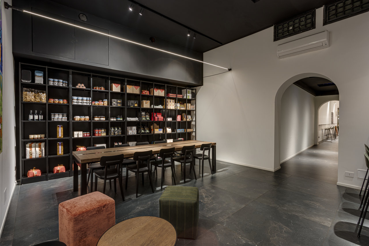 Modern showroom with dark floor tiles, long table, and elegant wall shelf.